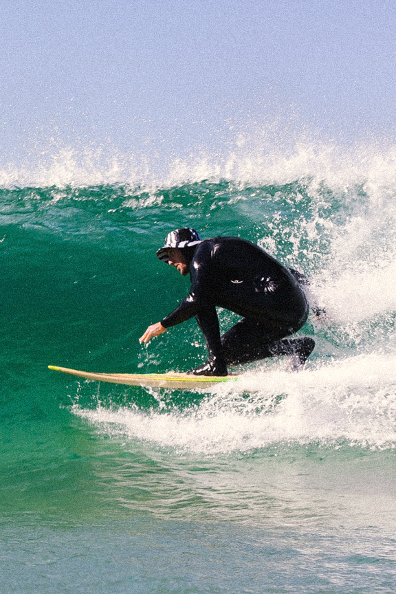 man surfing short board in zebra print surf hat with neck flap - el dingo
